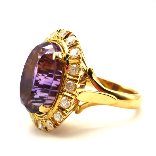 Side view of a large yellow gold cocktail ring set with a central purple amethyst with diamond surround
